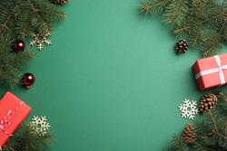 Frame made of Christmas decorations on green background, top view with space for text. Winter season