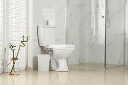 Toilet bowl near shower stall in modern bathroom interior