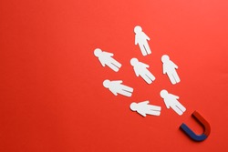 Magnet attracting paper people on red background, flat lay. Space for text