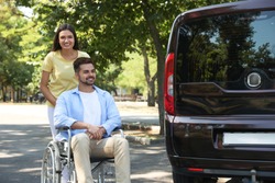 Young woman with man in wheelchair near van outdoors
