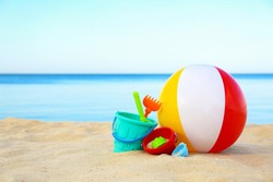 Set of plastic beach toys and colorful ball on sand near sea. Space for text