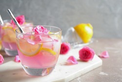 Delicious refreshing drink with lemon and roses on marble table