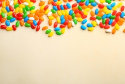 Colorful jelly beans on beige background, flat lay. Space for text