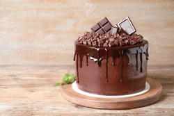Freshly made delicious chocolate cake on wooden table. Space for text