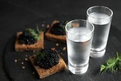 Cold Russian vodka and sandwiches with black caviar on table, closeup