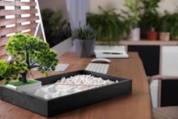Beautiful miniature zen garden and computer on wooden table in office