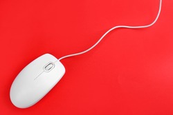 Modern wired optical mouse on red background, top view