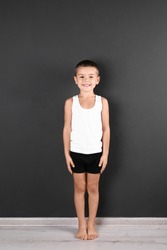 Cute little boy in underwear near dark wall