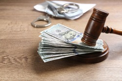 Dollar bills and gavel on wooden table. Bribe concept