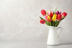 Beautiful spring tulips in vase on table against light marble background. Space for text