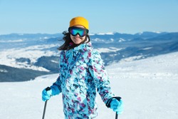 Female skier on snowy slope in mountains. Winter vacation