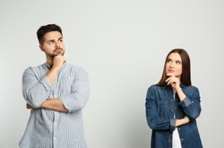 Pensive couple on light background. Thinking about answer for question
