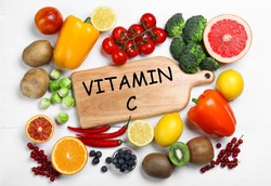 Board with phrase VITAMIN C and fresh products on white wooden table, flat lay