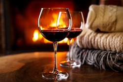 Glasses of wine, knitwear and blurred fireplace on background