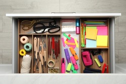 Stationery and sewing accessories in open desk drawer, top view