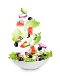Fresh ingredients for Greek salad falling into bowl on white background