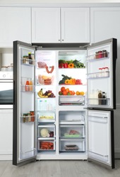 Open refrigerator filled with food in kitchen