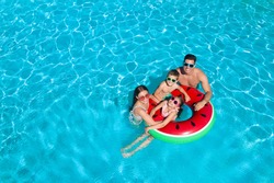 Happy family with inflatable ring in swimming pool, space for text. Summer vacation 