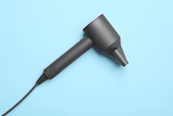 Hair dryer on light blue background, top view. Professional hairdresser tool