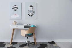 Child's room interior with desk and cute posters on light wall. Space for text