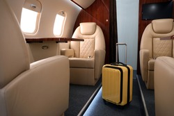 Airplane cabin with yellow suitcase. Air travel