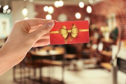Woman holding gift card in restaurant, closeup