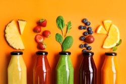 Flat lay composition with bottles of delicious juices and fresh ingredients on orange background
