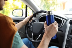 Man with thermos driving car, closeup view