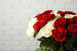 Luxury bouquet of fresh roses near white brick wall, closeup. Space for text