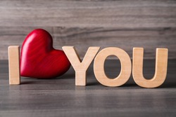 Phrase I Love You made of decorative heart and letters on wooden table, closeup
