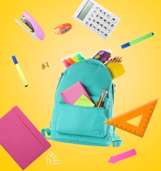 Backpack surrounded by flying school stationery on yellow background