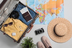 Flat lay composition with packed suitcase and travel accessories on grey background. Summer vacation