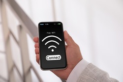 Man connecting to WiFi using mobile phone indoors, closeup