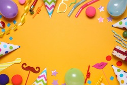 Frame of different party items and decorations with space for text on orange background, flat lay