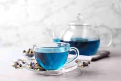 Glass cup of organic blue Anchan on light table, space for text. Herbal tea