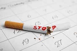 Broken cigarette with word Stop on calendar sheet. Quitting smoking concept