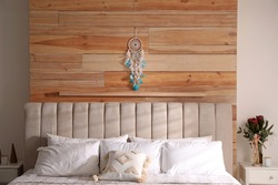 Beautiful dream catcher hanging above bed in stylish room interior