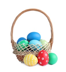 Wicker basket with bright painted Easter eggs on white background