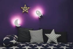 Room interior with bed and different night lamps on purple wall