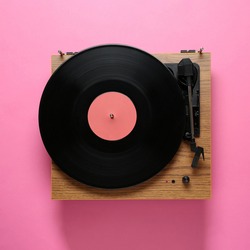 Modern turntable with vinyl record on pink background, top view