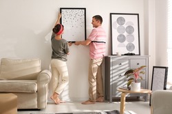 Couple decorating room with pictures together. Interior design
