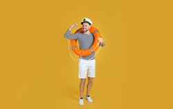 Sailor with orange ring buoy showing biceps on yellow background