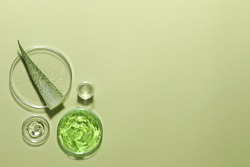 Organic cosmetic product, natural ingredients and laboratory glassware on green background, flat lay. Space for text