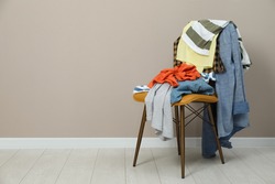 Different clothes on chair near light grey wall, space for text