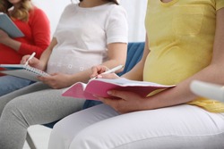 Group of pregnant women at courses for expectant mothers on blurred background, closeup