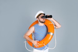 Sailor with binoculars and ring buoy on light grey background