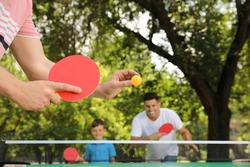 Family with child playing ping pong in park, closeup