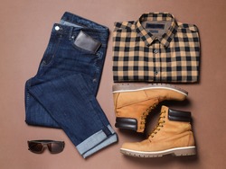 Flat lay composition with stylish men's clothes and boots on brown background