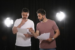 Professional actors reading their scripts during rehearsal in theatre