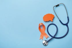 Orange ribbon, stethoscope and paper brain cutout on light blue background, flat lay with space for text. Multiple sclerosis awareness